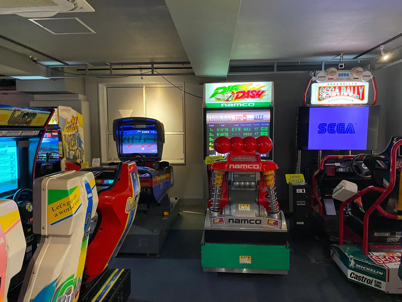 Retro Namco and Sega racing cabinets in a small Tokyo arcade
