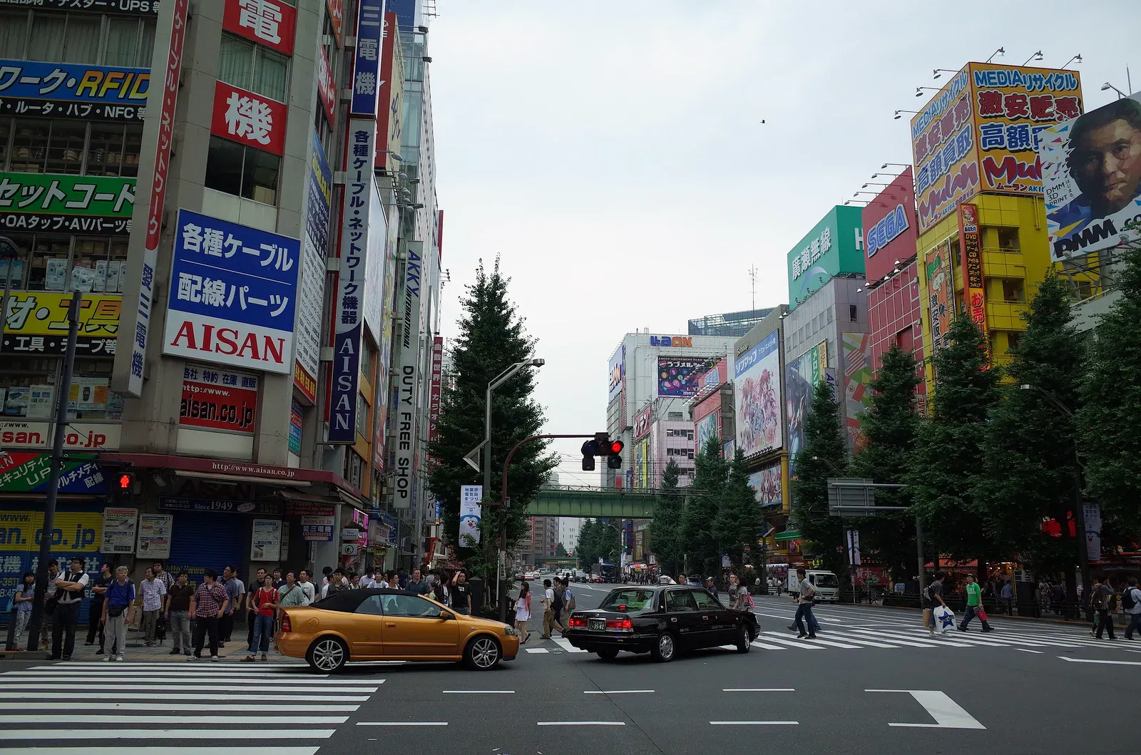 Akihabara street with a yellow taxi at the crossing and shop signs