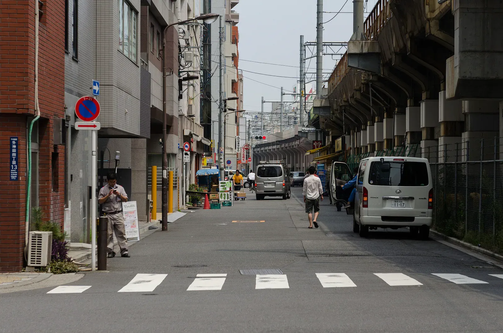 Quiet back street with a crosswalk and van beside a rail viaduct