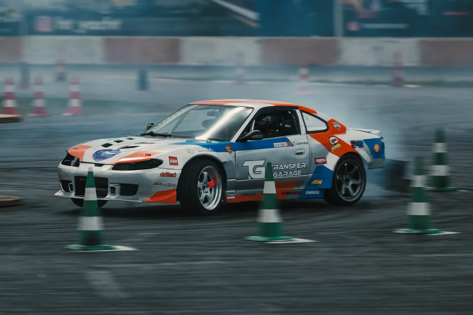 White coupe drifting between traffic cones on a practice course