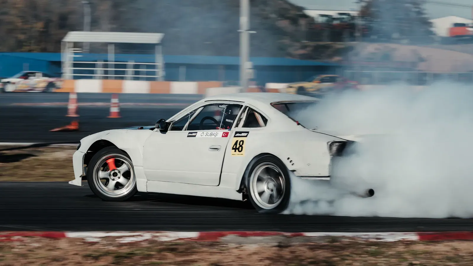 White sports car drifting through thick tyre smoke on a track