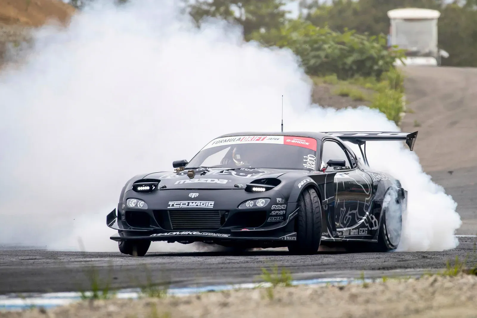 Black drift car engulfed in a huge cloud of white tyre smoke