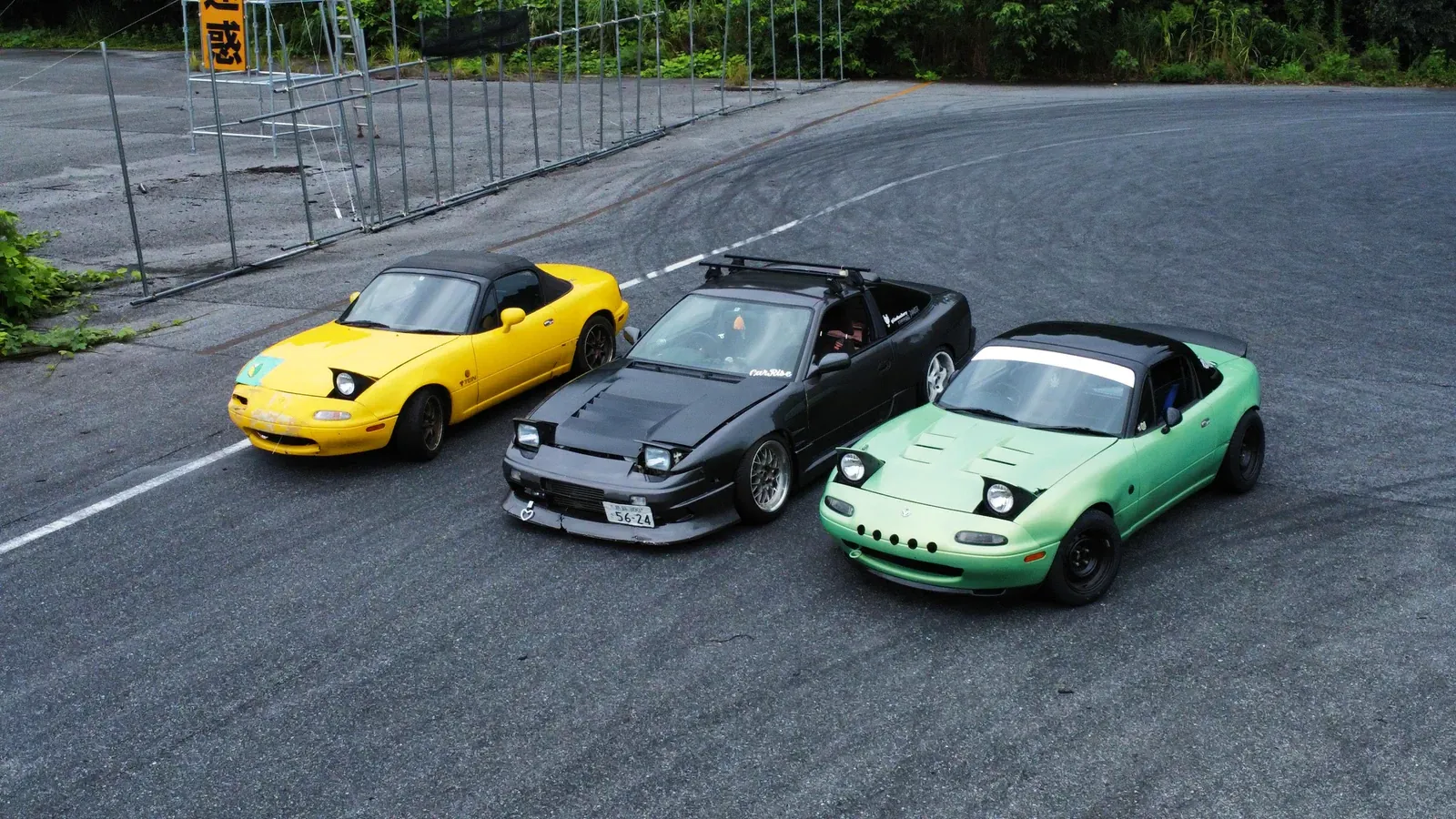 Yellow, black and green roadsters parked on an empty practice tarmac