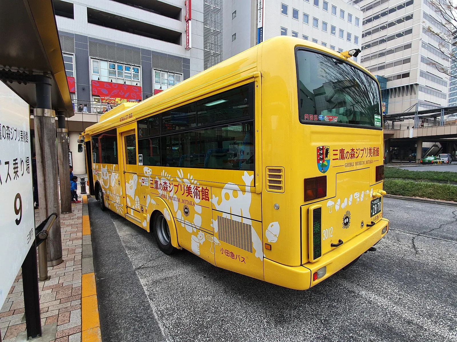 Yellow museum shuttle bus parked at a city bus stop