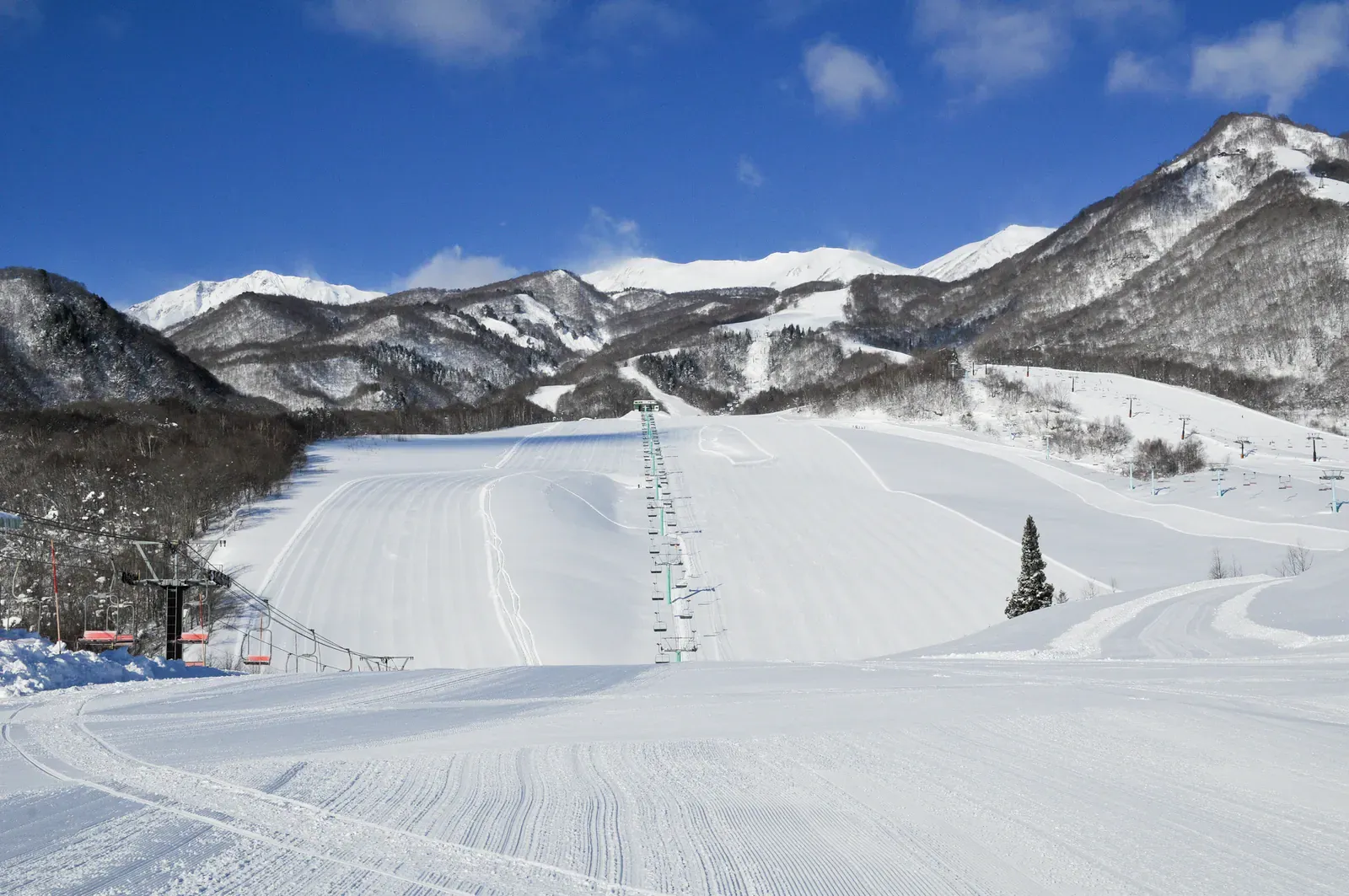 Snowy ski slope below Northern Alps peaks at Tsugaike, Nagano