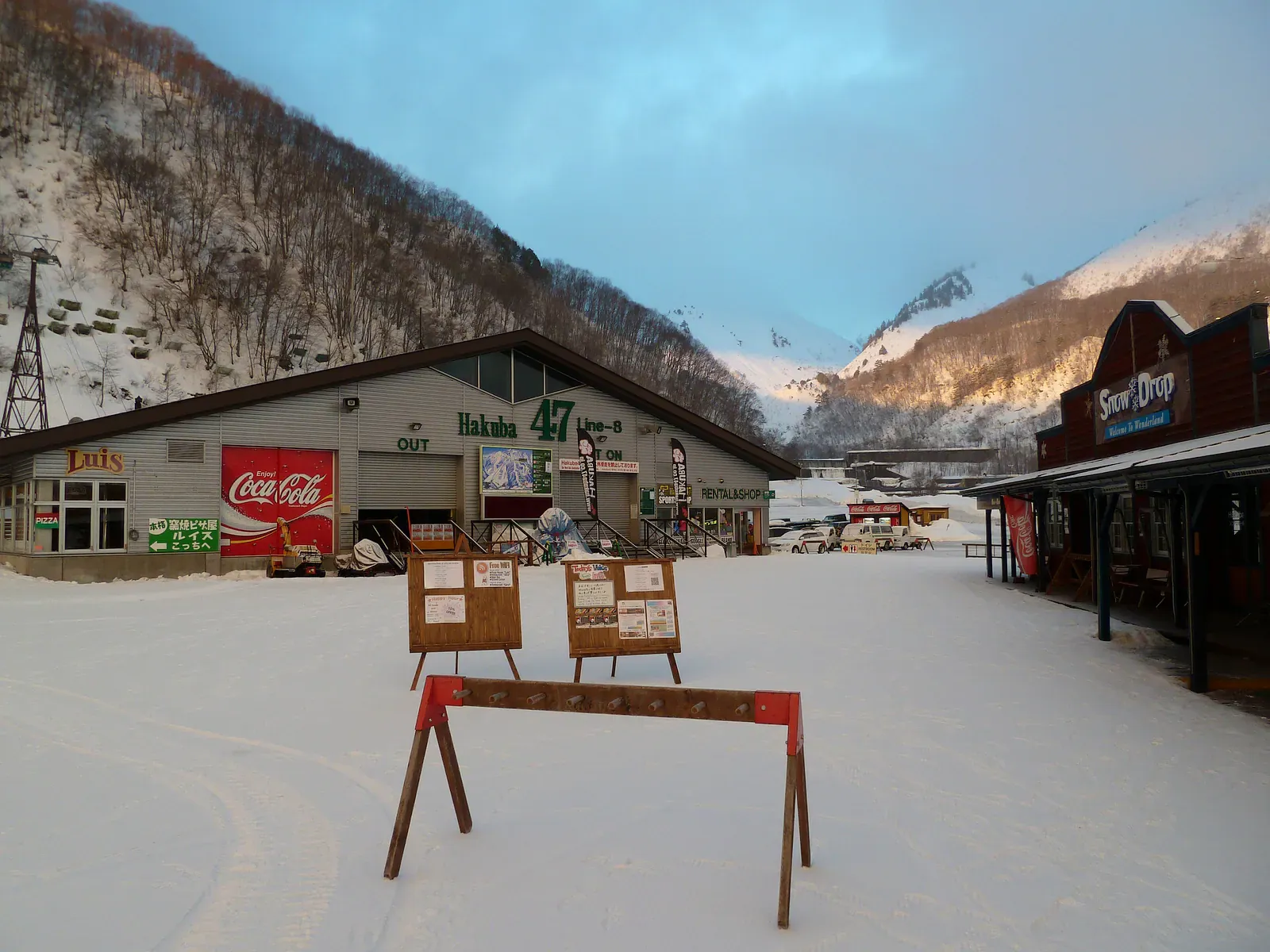Snowy ski base lodge with a Coca-Cola sign and a snow barrier