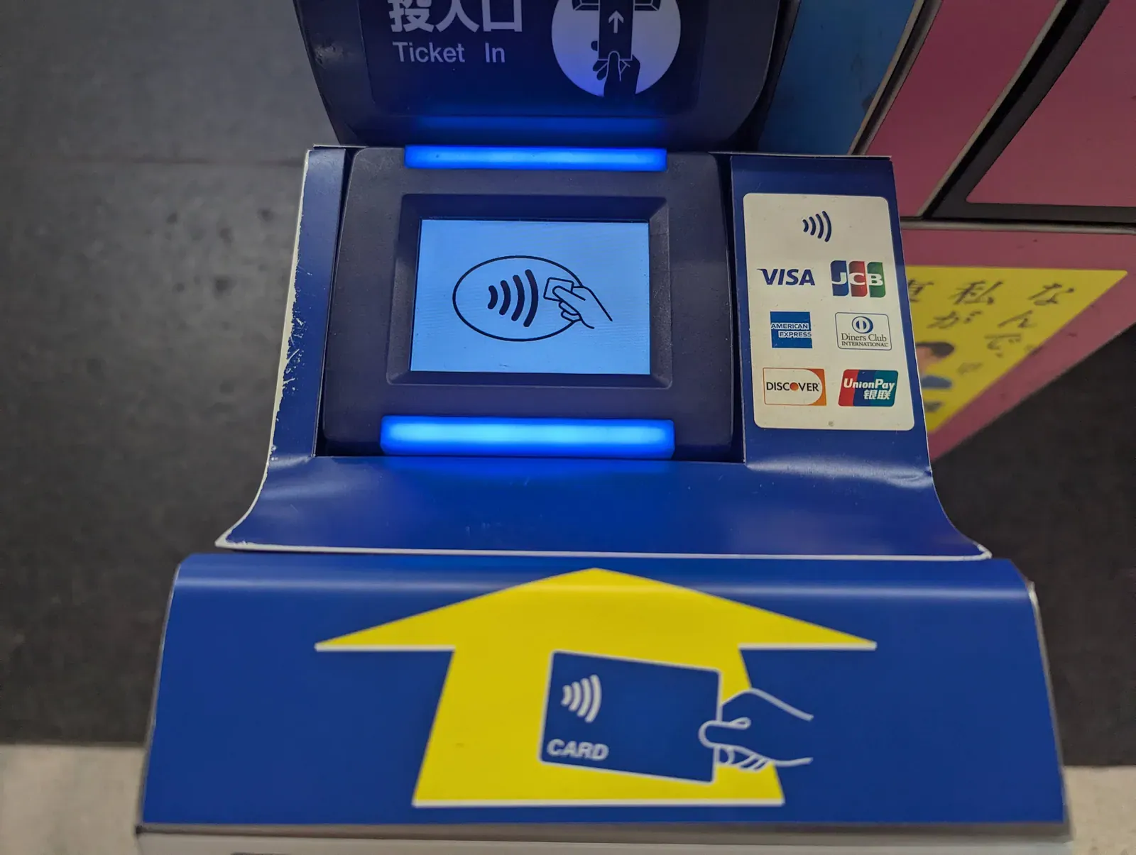 Blue ticket gate card reader with a contactless card symbol and arrow