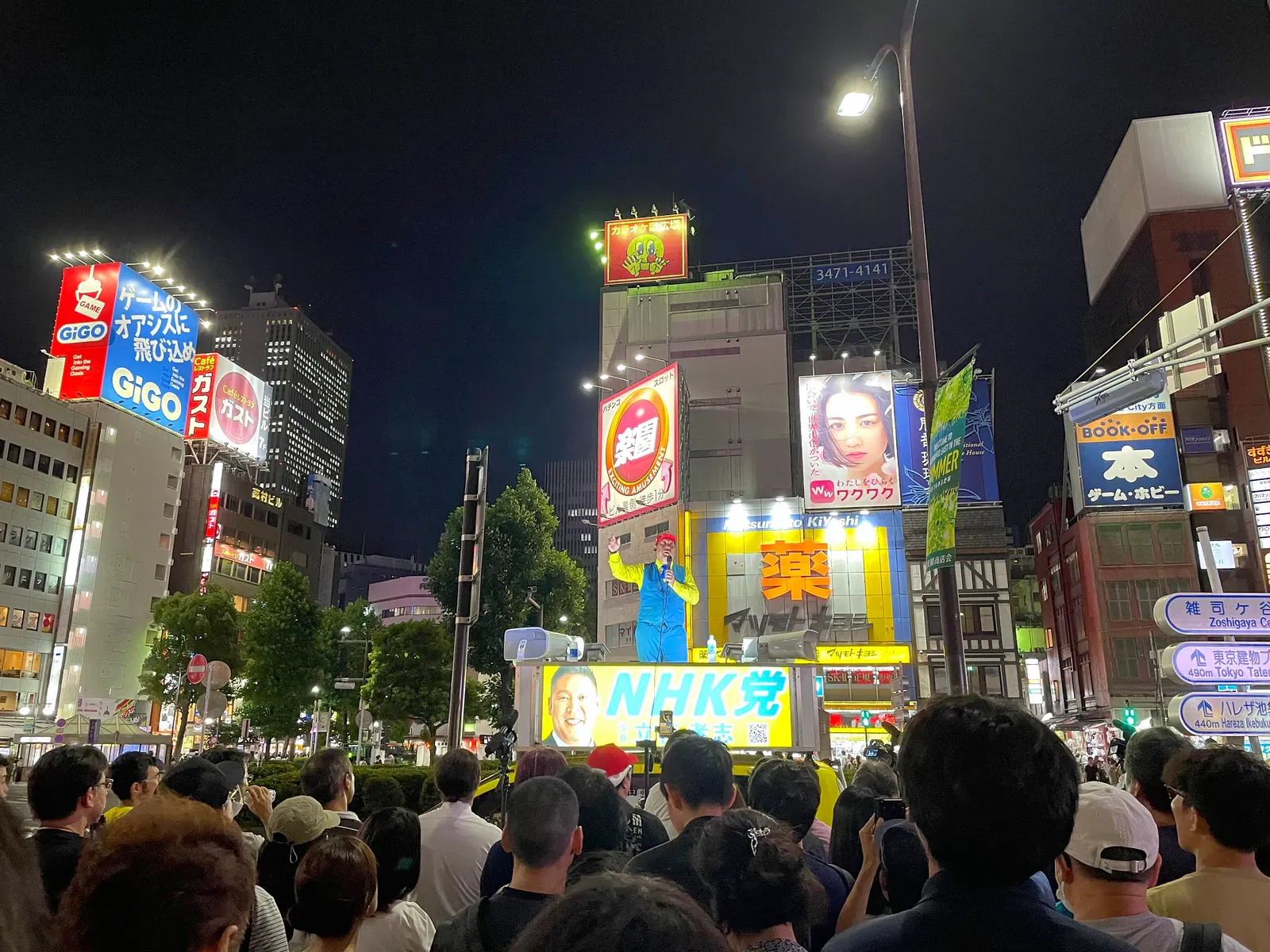 Crowd on a Tokyo street at night under neon signs and billboards