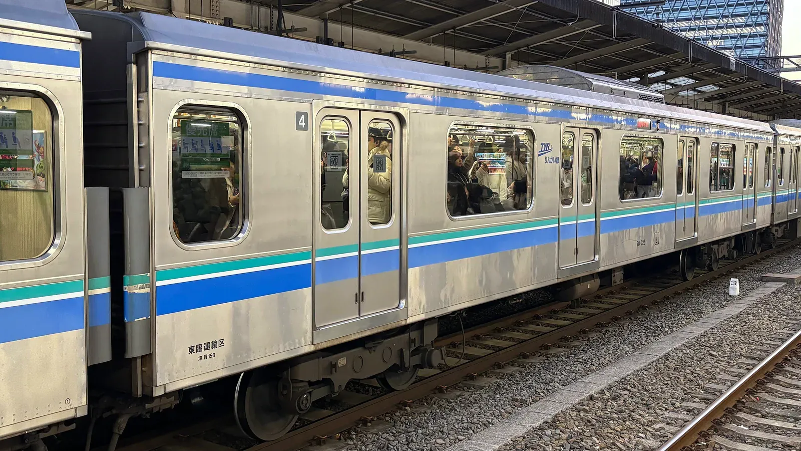 Blue-striped commuter train beside the track on a sunny day