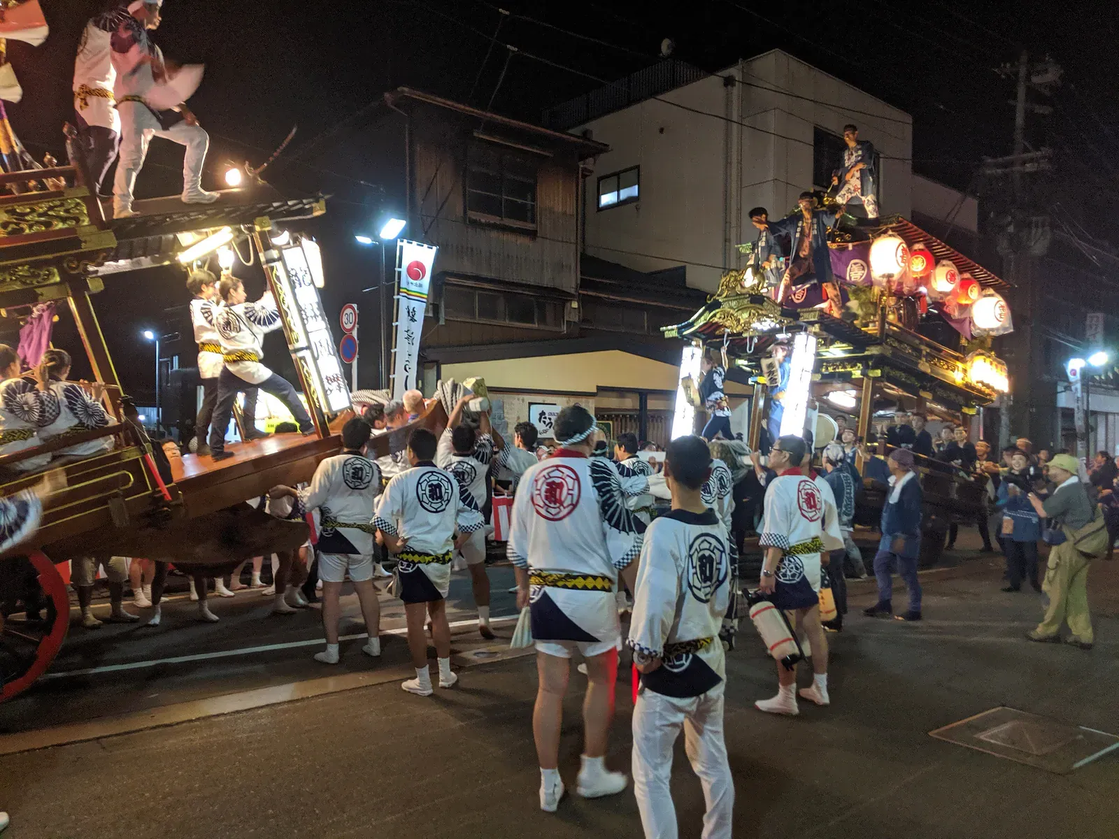 Lantern-lit festival float at night surrounded by crew in happi coats