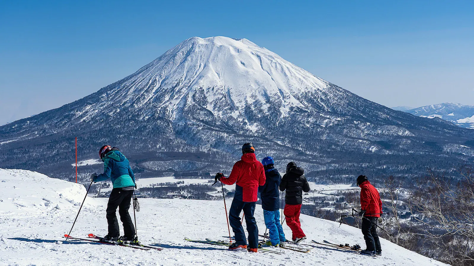 Skiers looking at Mount Yotei from the slope