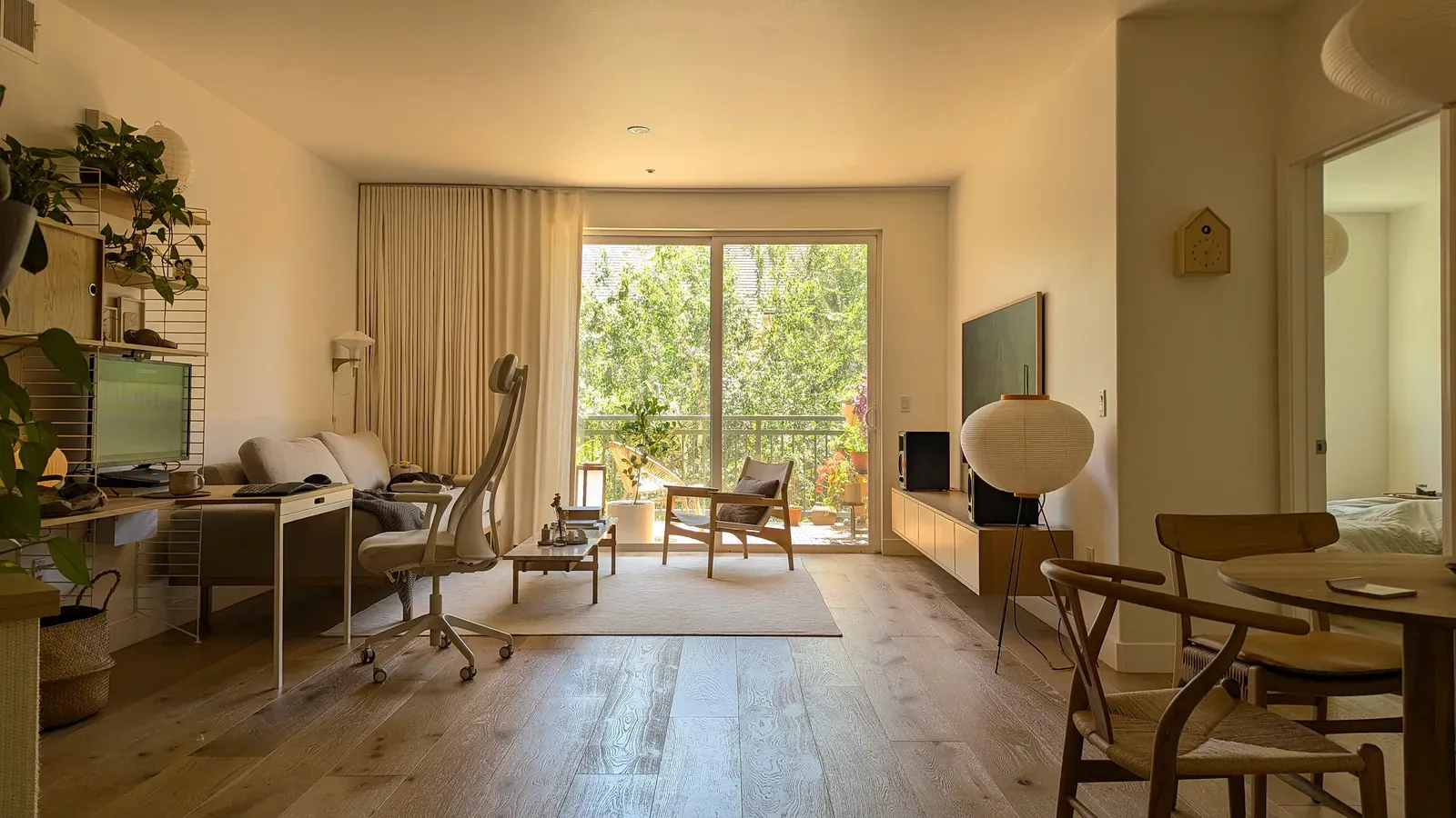Bright open-plan apartment with wooden floor, desk and balcony window