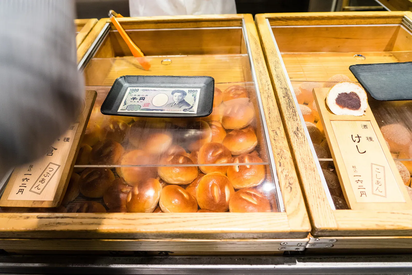 Yen note lying on a tray beside buns at a Japanese food stall