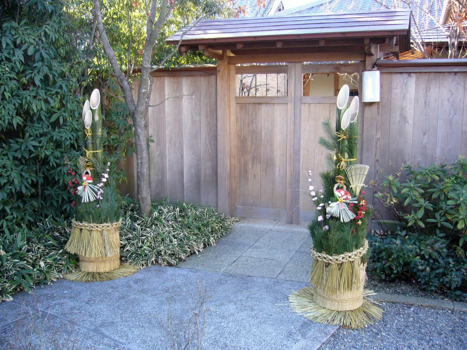 Pair of kadomatsu bamboo and pine new year decorations beside a gate