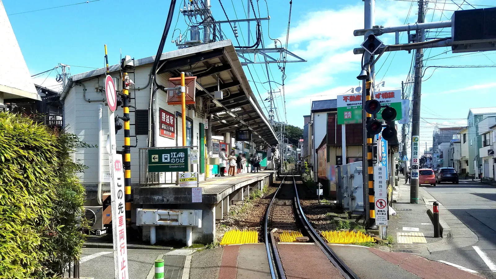 Small railway crossing and station platform under a blue sky
