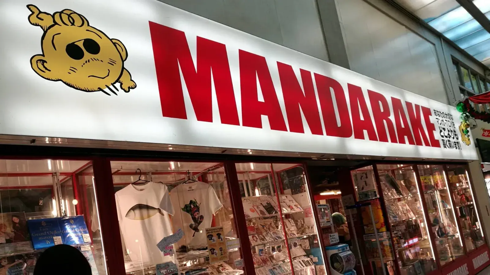 Red Mandarake shop sign above a window of figures and shirts