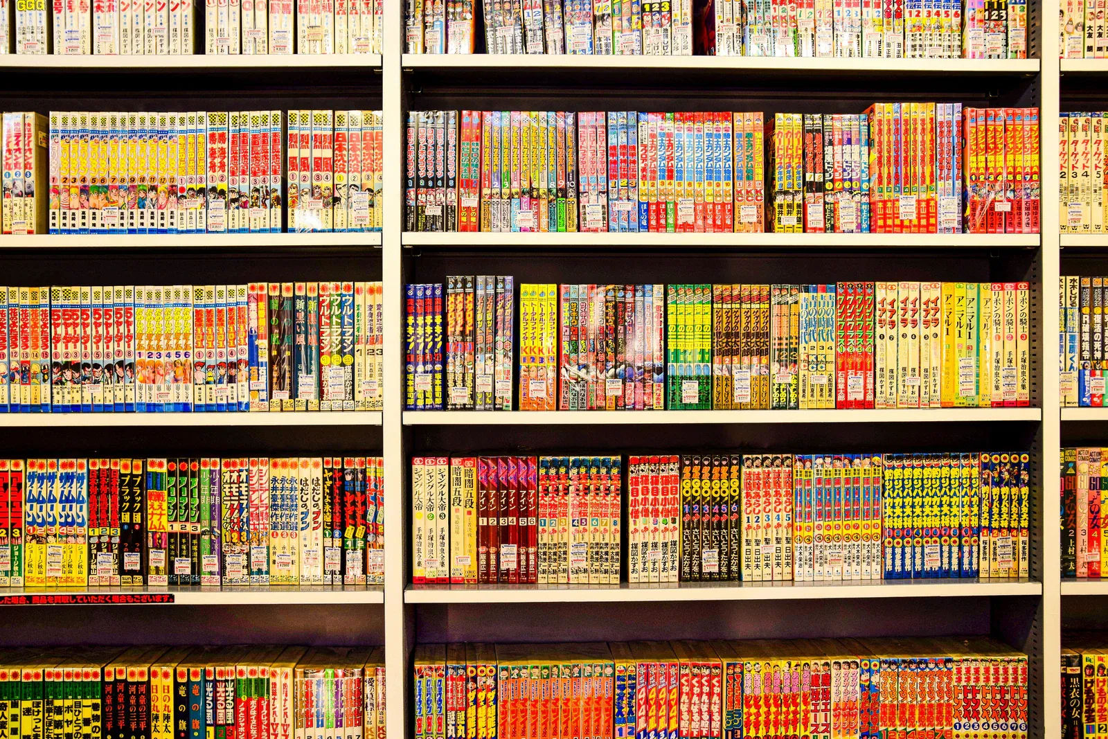 Floor-to-ceiling shelves packed with colourful manga volumes in a Japanese bookstore
