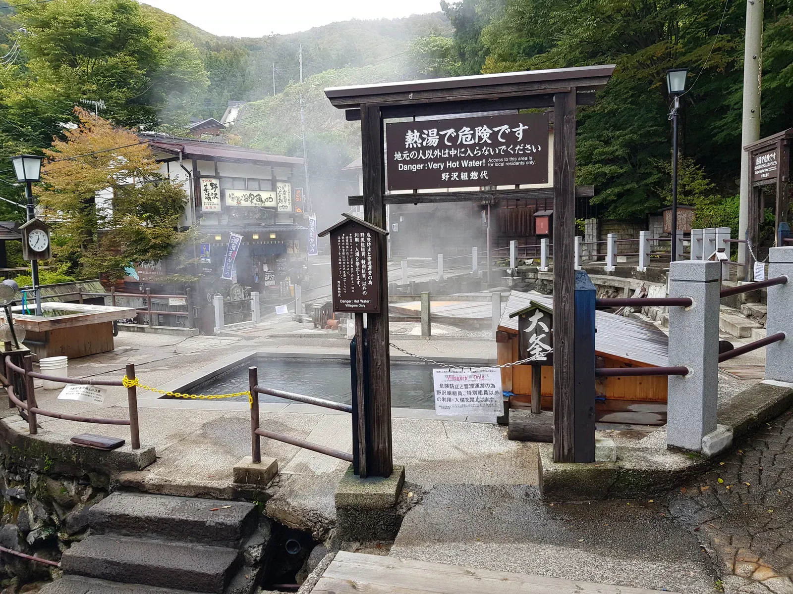 Steaming public hot spring pool with a wooden gate in Nozawa Onsen