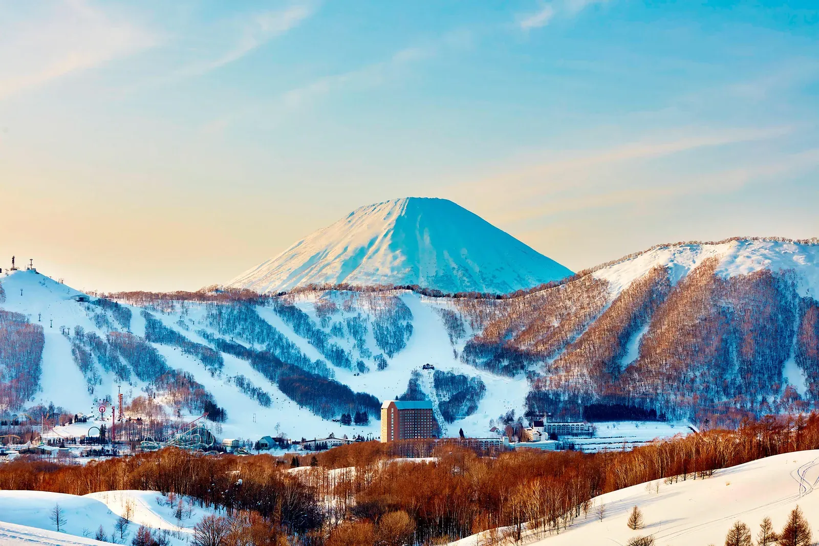 Snowy Rusutsu ski slopes below a perfectly conical mountain at dawn