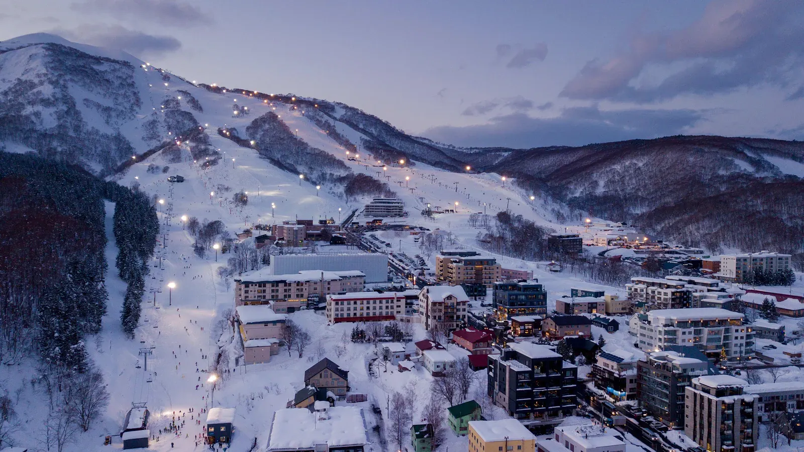 Snowy ski resort village and slopes at dusk in Hokkaido