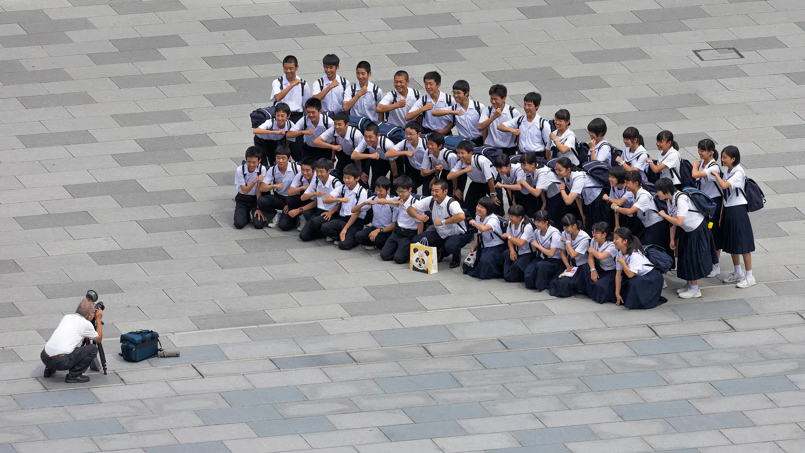 Schoolchildren in uniform posing for a group photo on a plaza