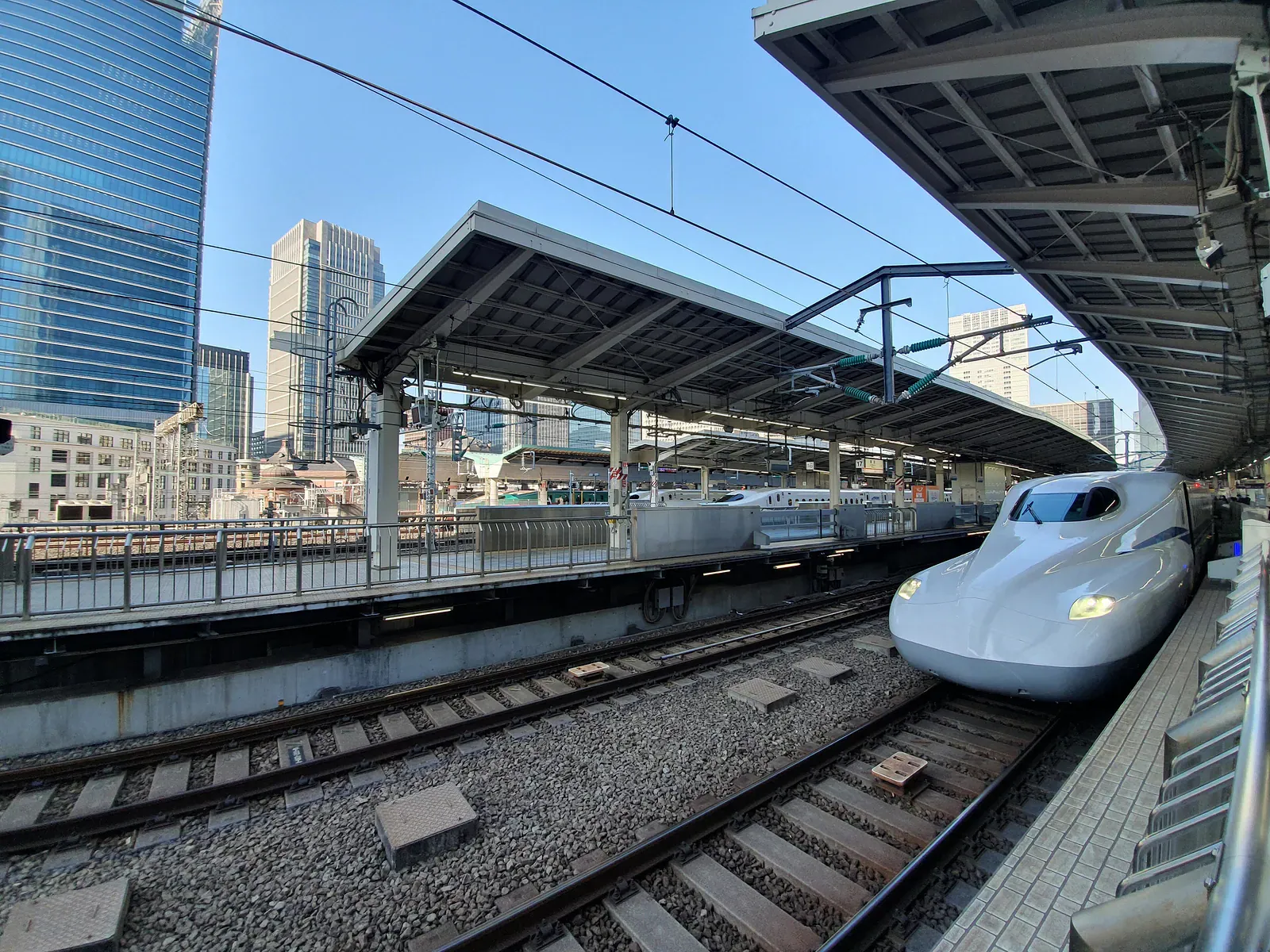 White Shinkansen arriving at a platform among skyscrapers