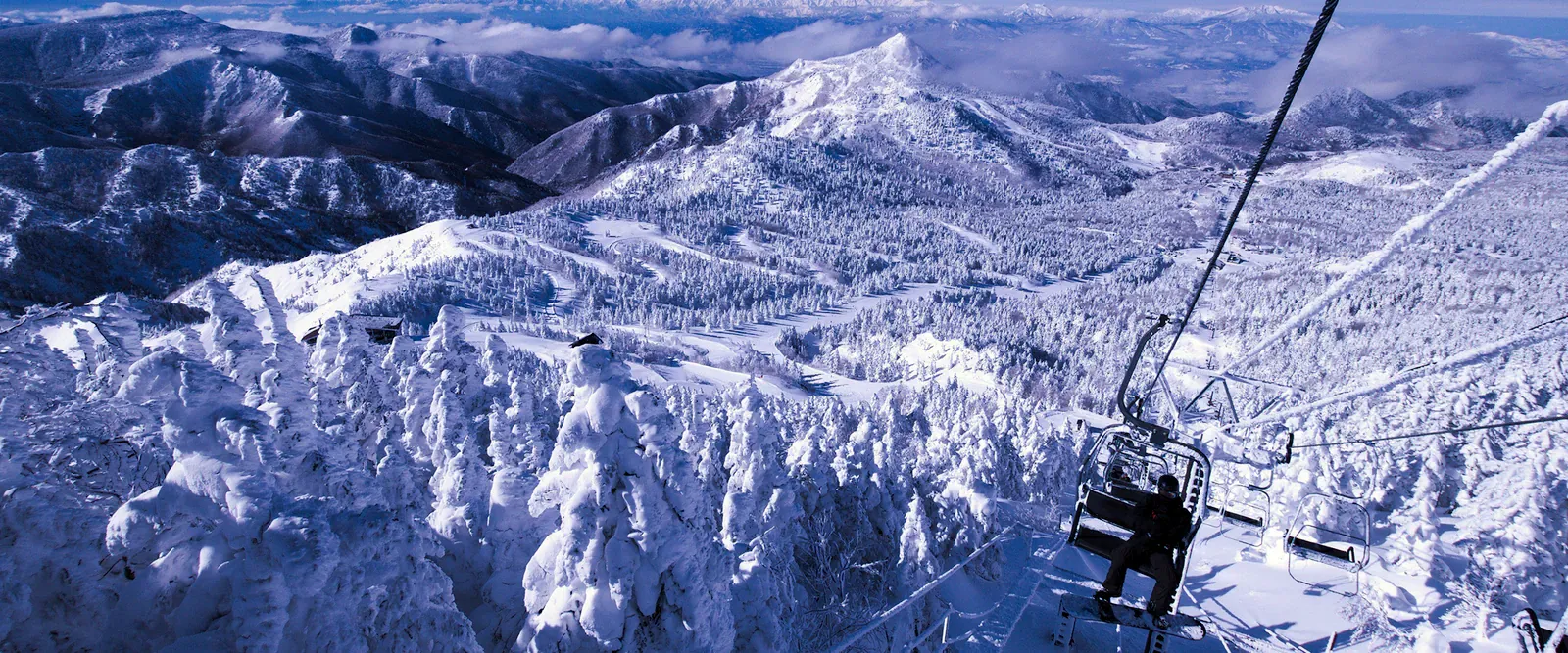 Chairlift above snow-covered peaks at Shiga Kogen